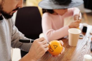 father and daughter making jack o lantern from an orange fruit